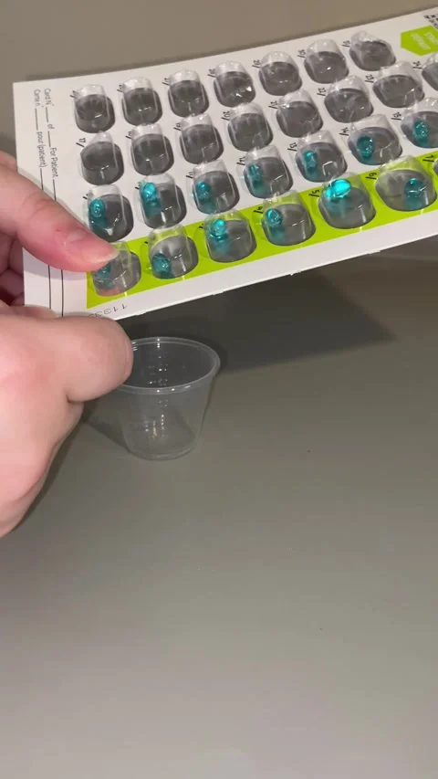 4K Pill being pushed out of a blister pack into a small cup Stock Footage 318625448