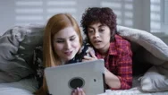 4K Portrait Of Gay Female Couple Relaxing In Bed With Computer Tablet Stock Footage
