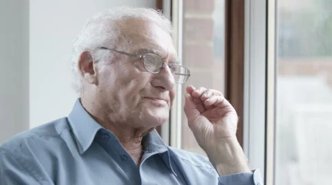 4K Portrait of sad elderly man sitting by the window.  Vidéo 63274969