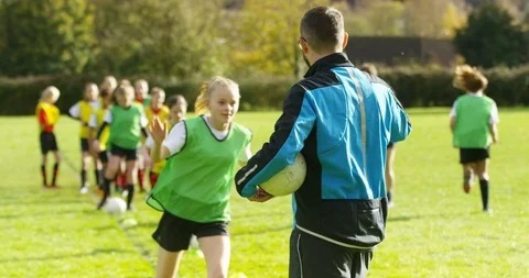 4K Portrait smiling coach, training with girls' soccer team on sports field Stock Footage 86288626