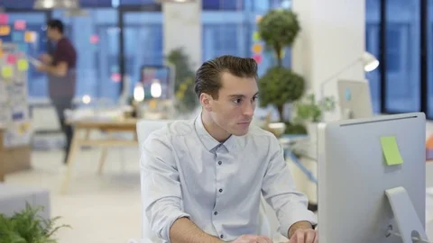 4K Portrait smiling designer working on computer at his desk in creative office 動画素材 76006436