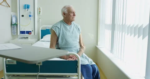 4K Portrait of smiling elderly patient sitting on his bed in hospital room Stock Footage 62997744