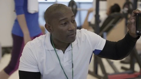4K Portrait smiling personal trainer supervising a client in modern gym Stock Footage 75850164