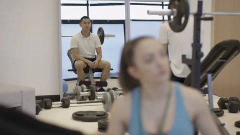 4K Portrait smiling personal trainer supervising a client in modern gym Stock Footage 75850723