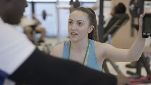 4K Portrait smiling personal trainer supervising a client in modern gym Stock Footage 75850899
