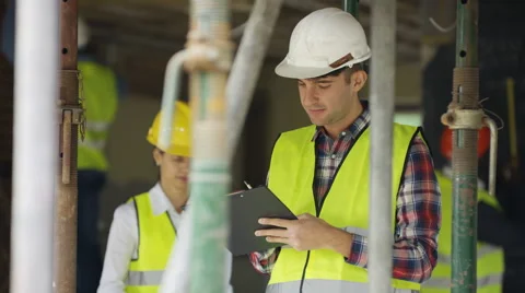 4K Portrait smiling worker at construction site writing notes on clipboard Stock Footage 65130367