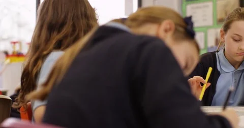 4K Portrait unhappy or bored little girl working at communal table in classroom Video stock 74267953