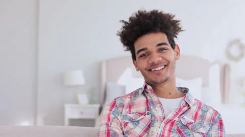 4k Portrait of young curly guy is posing for camera and sitting on sofa in Stock Footage 195080932