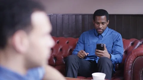 4K Portrait Of Young Man Sitting In Coffee Shop Looking At Smartphone Stock Footage 75777583