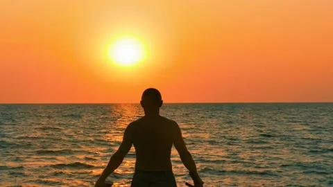 4К. Prayer man take cross and Bible up  against  marine sunset or sunrise . Stockbeeldmateriaal 103676716