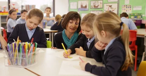4K Primary school children drawing in the classroom with teacher helping Stock Footage 74229715