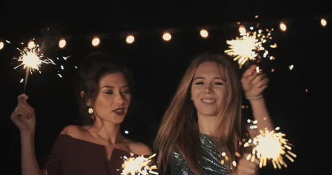 4k ProRes 422. two dancing girls laughing and smiling burn and waving sparklers Stock Footage 161593830