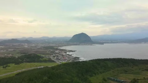 4K Pull-off Aerial View of Mt.Sanbansan (산방산) passing Mt. Songaksan (송악산), Jeju Stock Footage 143864125