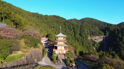 4K Pullback of a Red Japanese Temple with 3-Story Pagoda and Waterfall Stock Footage 257796030