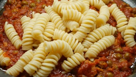 4k, putting pasta in pan cooked with tomato, tuna Stock Footage 82773396