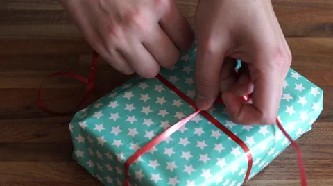 4K Putting red string around a paper wrapped present/gift Stockbeeldmateriaal 55290757