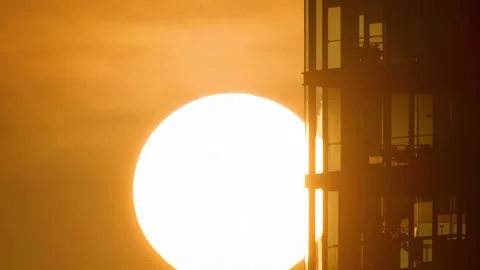 4K - Real movement of the sun at sunset behind the skyscraper Stock Footage 142589448
