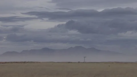 4K real time of a distant lone windmill in a winter dust storm on Arizona plains Video stock 229326003