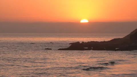 4K real time shot of half of the setting sun behind a distant fog bank in Malibu Stock Footage 138207770