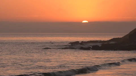 4K real time shot of the sun setting below a distant fog bank in Malibu Stock Footage 138209244