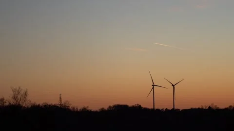 4k real time video of two wind turbine silhouettes at sunset. Green energy an Stock Footage 306140048