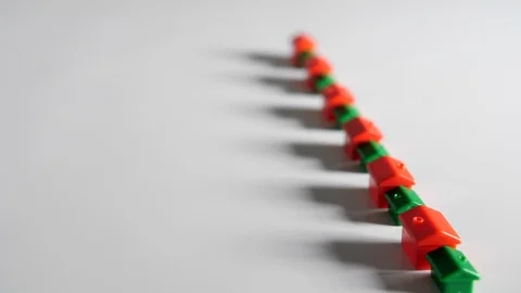 4K red and green plastic houses a row white background surface, representing  Stock Footage 90802958