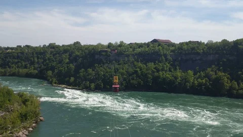 4K: red cable car on sturdy metal cables moving over a green emerald water 库存影片 110708678