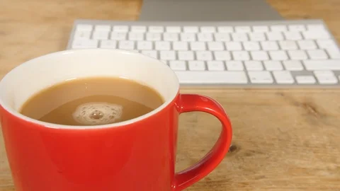 4K a Red cup of tea spinning in mug, hot drink at home computer work desk  Stock Footage 88502427