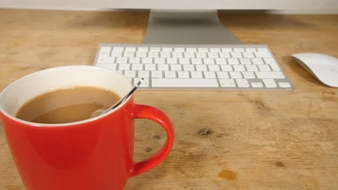 4K Red cup of tea spinning in mug, hot drink at computer work desk with teaspoon Stock Footage 88502881