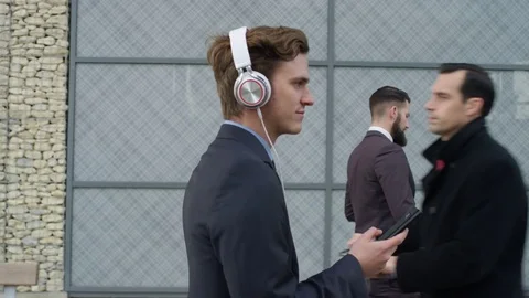 4K Relaxed businessman wearing headphones as he walks to work Stock Footage