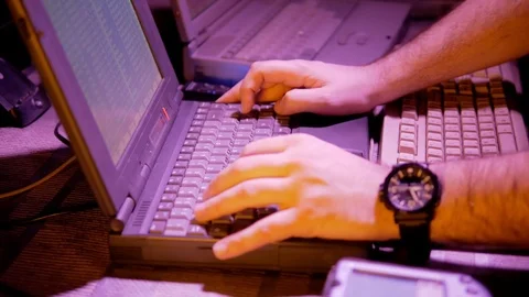 4k Retro cyber neon light at hackers room who works with old laptops hands close Stock Footage 86206175