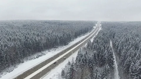 4K. Road in the winter forest with driving cars at snowfall. Aerial view. Stock Footage 79156970