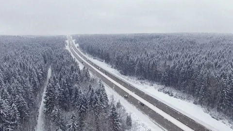 4K. Road in the winter forest with driving cars at snowfall. Aerial view. Stock Footage 80910386