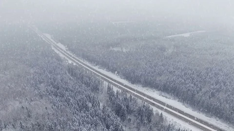 4K. Road in the winter forest with driving cars at snowfall. Aerial view. Stock Footage 80917115