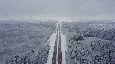 4K. Road in winter forest with driving cars at snowfall. Aerial view. Video stock 84443850