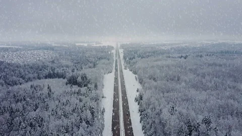 4K. Road in winter forest with driving cars at snowfall. Aerial view. Stock Footage 98430436