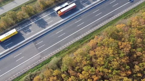 4K Rocket Drone Shot Rising Above Busy Highway Surrounded by Colorful Forest Видео 320883832