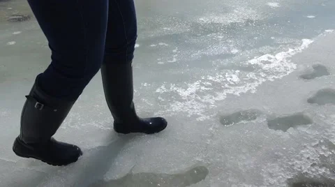 4k rubber boots walking through slush water ice and snow Stock Footage 61374454