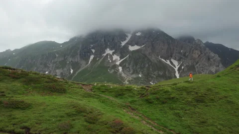 4K runner running along ridge in Italian Alps wearing orange windbreaker jacket Stock Footage 201632729