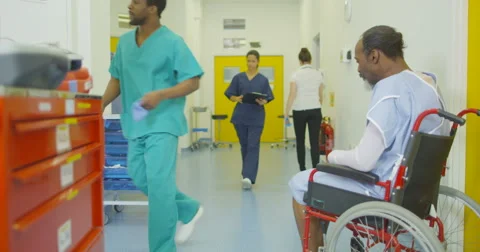 4K Sad man sits alone in his wheelchair in busy hospital area Stock Footage 63003349
