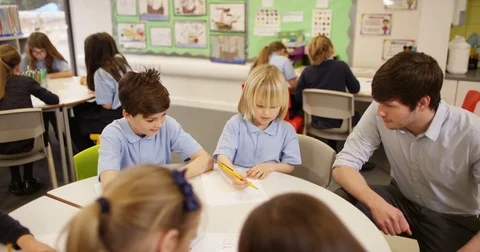 4K School children drawing in the classroom with little boy talking to teacher Stock Footage