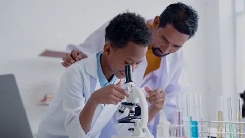 4K, Schoolboy studying under a microscope with Asian male teacher Stock Footage 232490590