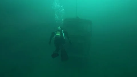 4K scuba diver exploring a submerged double decker bus underwater in quarry 動画素材 188545557