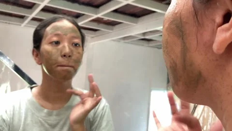 4K Selective Focus: Young Woman Applying Herbal Face Mask in Mirror Video stock 335010355