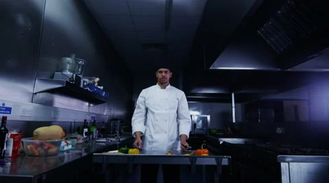 4K Serious chef in dark commercial kitchen holds knives above his head Stock Footage