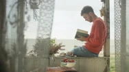 4K Serious Man Reading A Book At Beach House, Enjoying The Peace, Tranquility Stock Footage