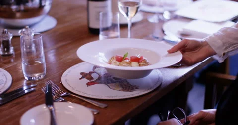 4K Server sets down a customer's dish on the table in gourmet restaurant Stock-Footage 62909691