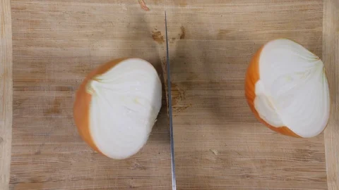 4K sharp kitchen knife slicing brown onion on chopping board in half Stock Footage 88486529