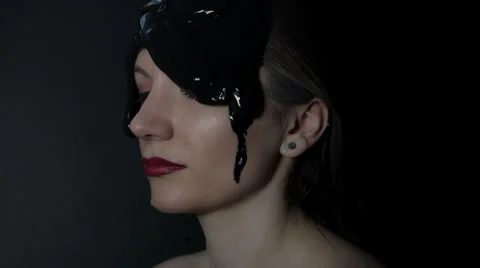 4k shoot of a model in studio with black mud pouring on her face Stock Footage 64673260