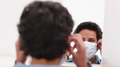 [4k] short haired latino woman putting off face mask while looking at mirror Stock Footage